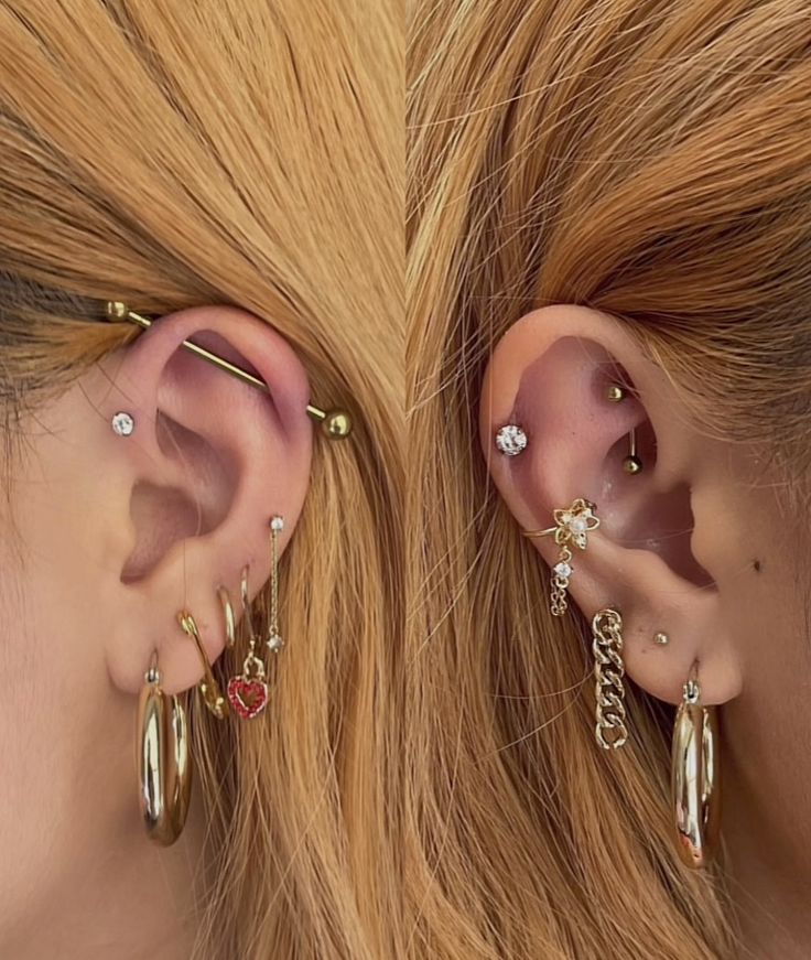 two women wearing gold ear piercings with red stones and chains on their ears, one is