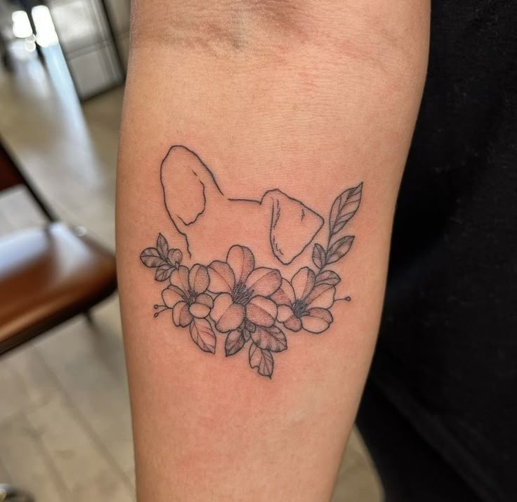 a black and white photo of a dog with flowers on it's arm,