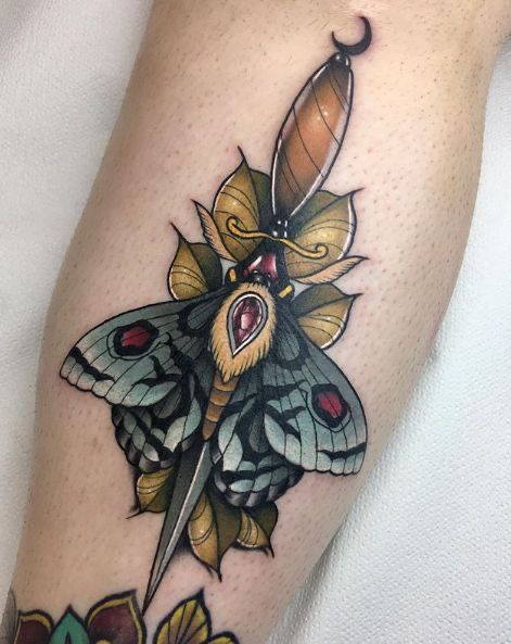 a close up of a person's leg with a butterfly on it and a knife