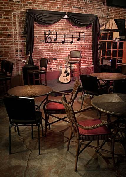 a room filled with lots of tables and chairs next to a guitar on the wall