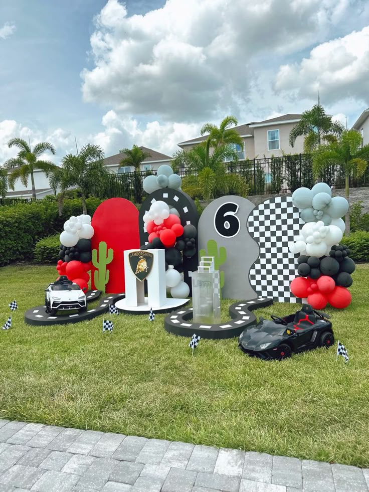 a lawn decorated with balloons and decorations for a race car themed birthday party or baby shower