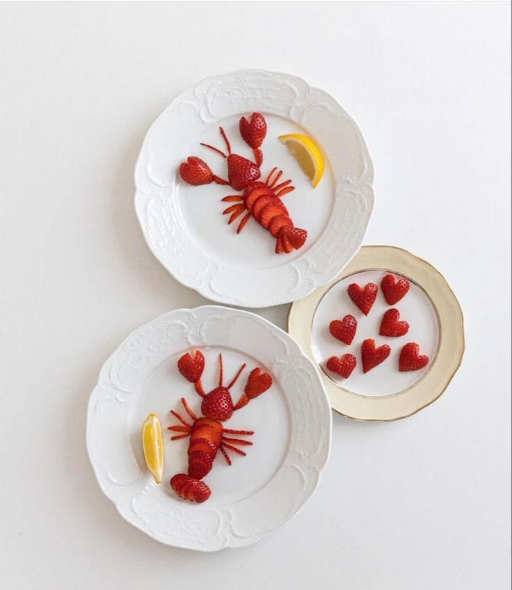 two white plates topped with lobsters and lemon slices on top of each other,