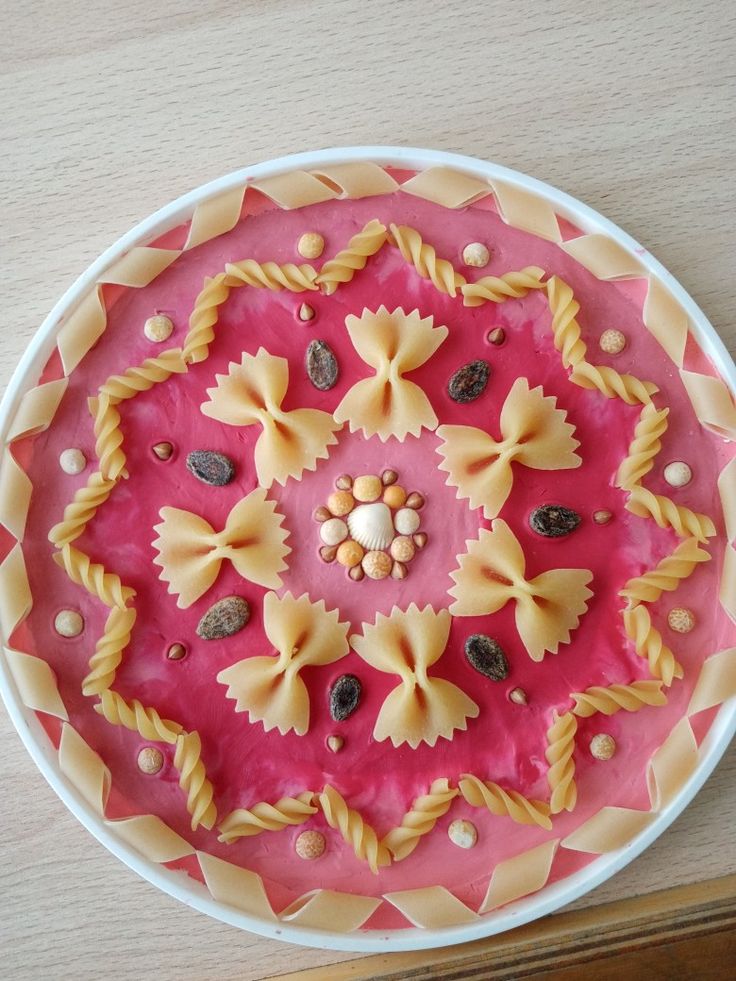 a pink and white plate with pasta on it