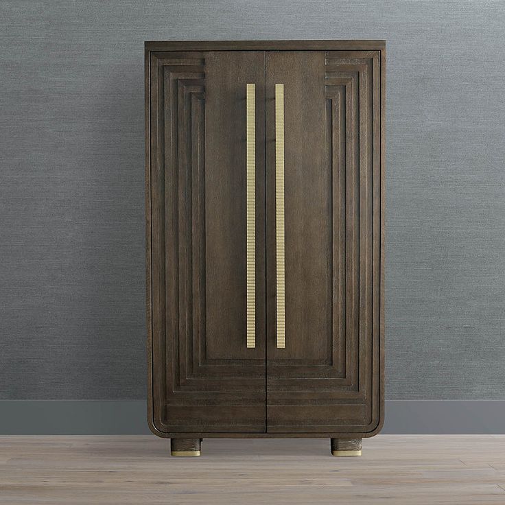 a tall wooden cabinet with gold trim on the bottom and sides, against a gray wall