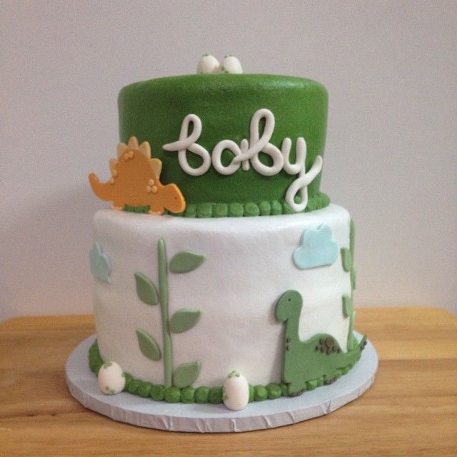 a green and white baby shower cake sitting on top of a wooden table