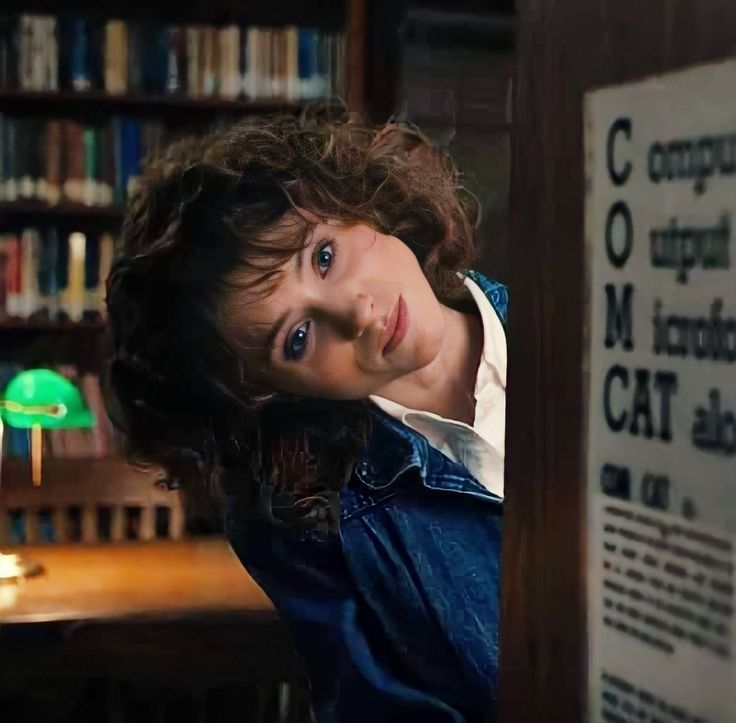 a woman leaning against a book shelf in a library