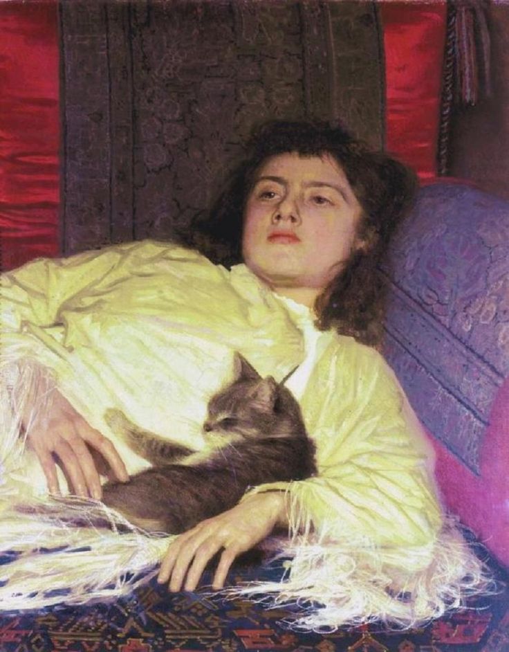 a woman laying on top of a couch next to a cat