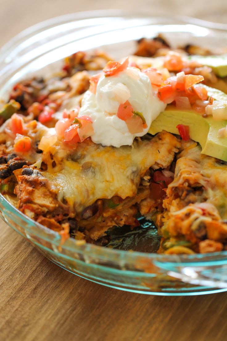 a casserole dish with meat, vegetables and sour cream in it on a wooden table