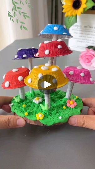 a person holding up a small mushroom house made out of cake paper and fondant