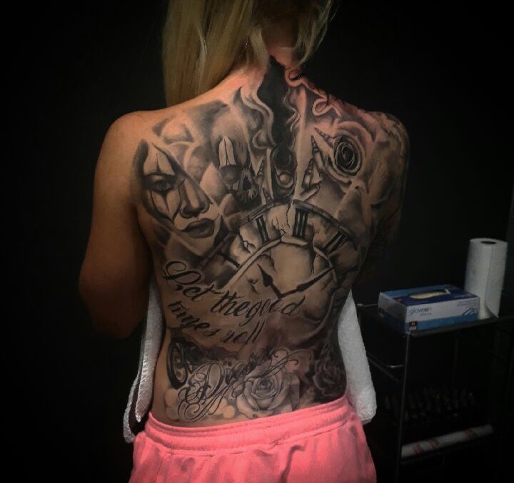 a woman with tattoos on her back is standing in front of a mirror and looking at the clock