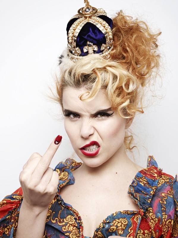 a woman with red lipstick and a crown on her head is pointing to the side