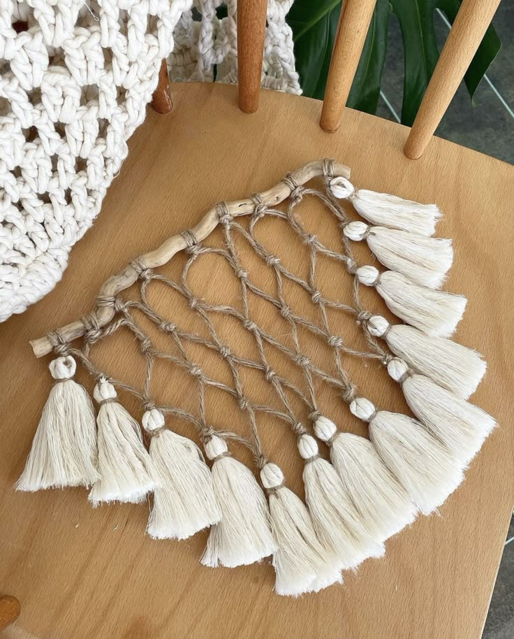 a wooden chair with white tassels on it and a crochet doily hanging from the back