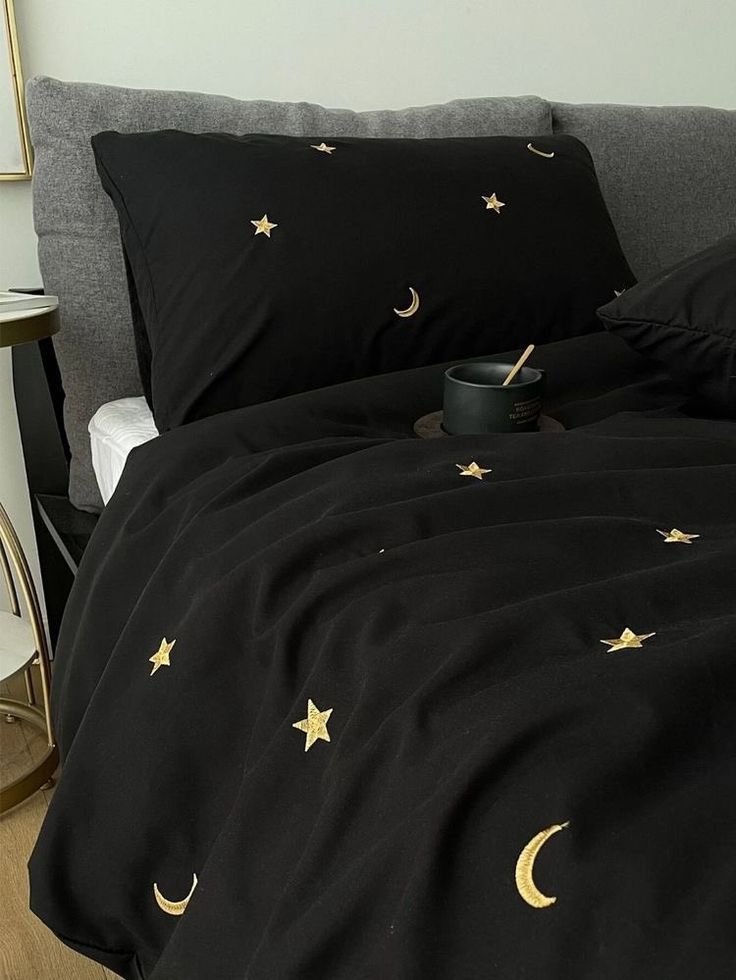 a bed with black sheets and gold stars on it