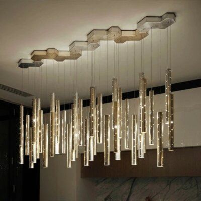 a modern chandelier hanging from the ceiling in a room with marble counter tops