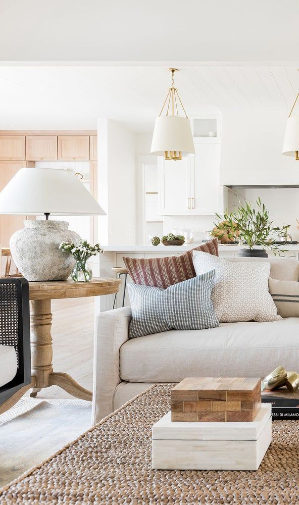 a living room filled with lots of furniture and pillows on top of a rug next to a coffee table