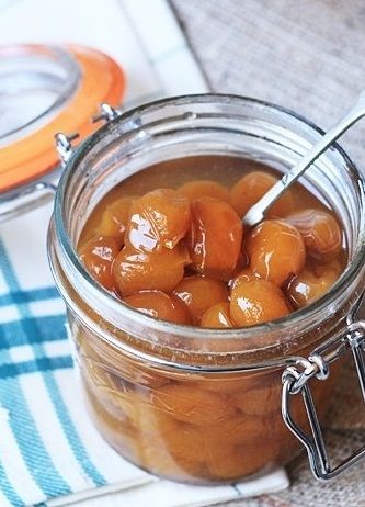 a glass jar filled with cherries sitting on top of a blue and white towel