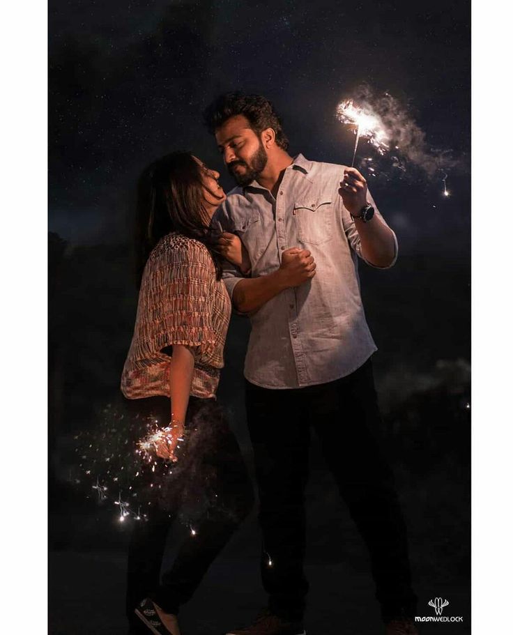 a man and woman holding sparklers in their hands while standing next to each other