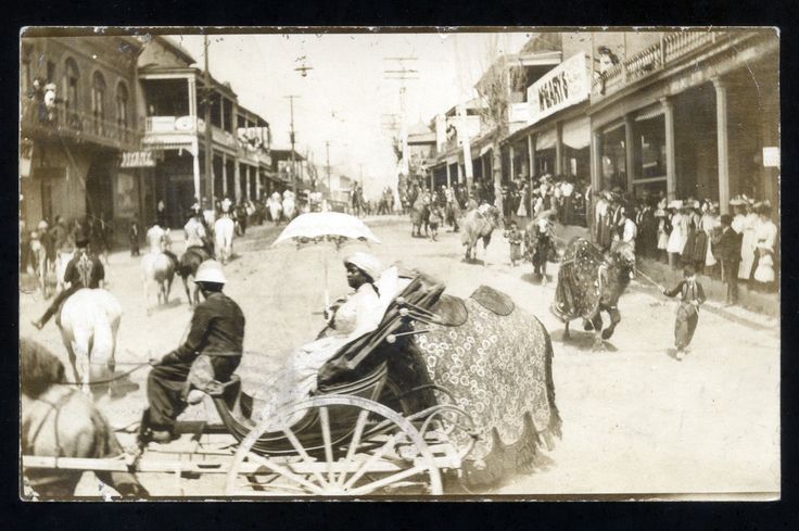 an old black and white photo of people riding in a horse drawn carriage down a city street