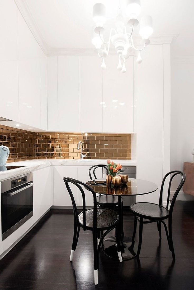 a kitchen with white cabinets and black chairs in front of a table that has a vase on it