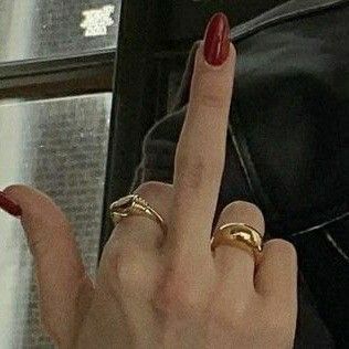 a woman's hand with two rings on it and one finger pointing at the camera