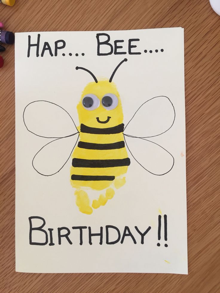 a happy birthday card with a bee drawn on the front and bottom, surrounded by crayons