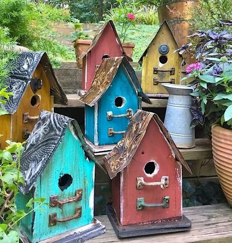 colorful birdhouses are lined up in the garden