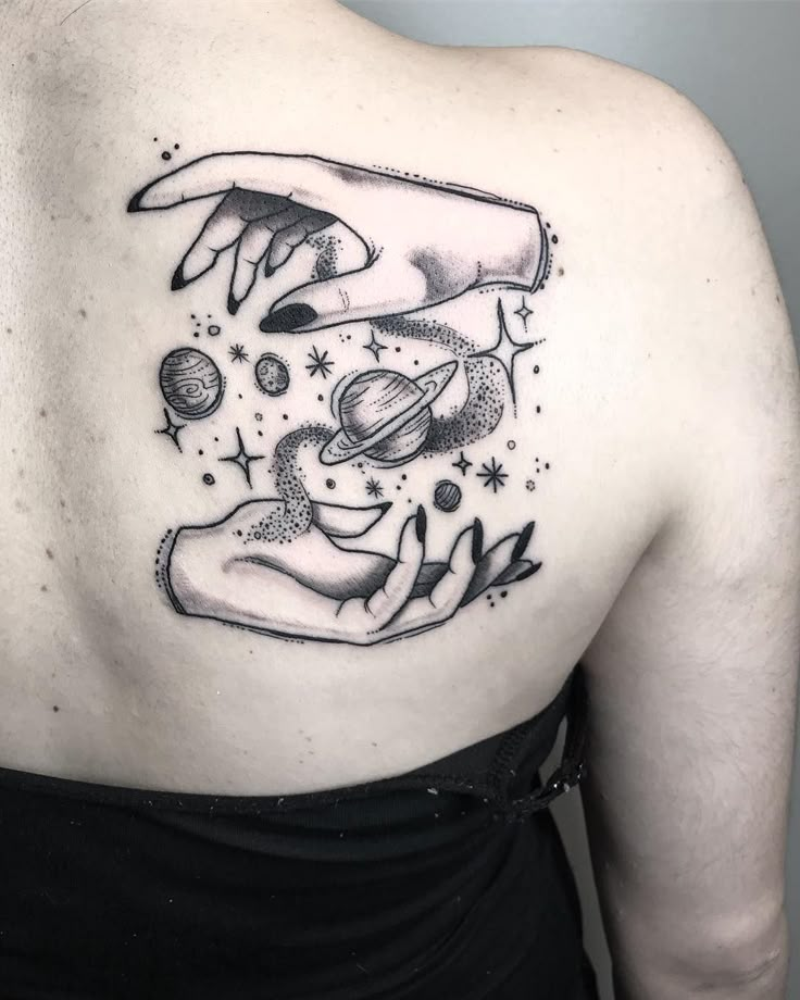 a woman's back with an image of two hands touching each other and planets in the sky