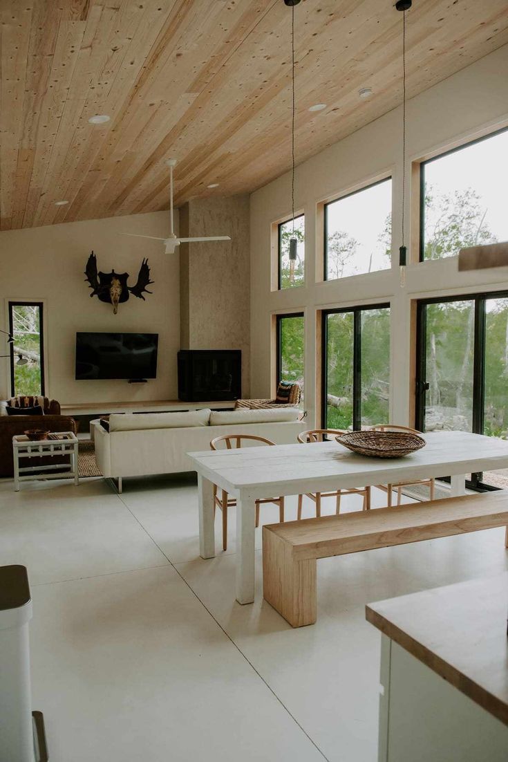 a living room filled with furniture and windows next to a flat screen tv on top of a wooden ceiling