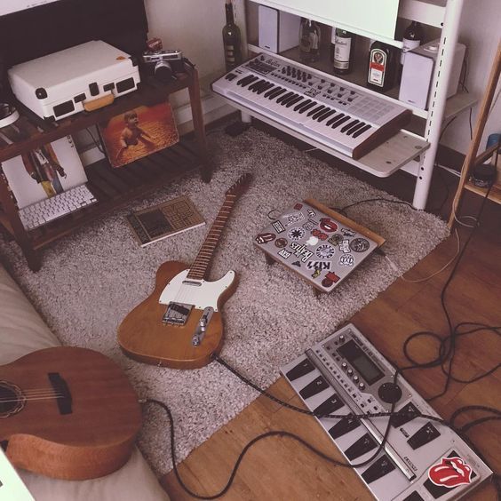 a living room with guitars and other musical equipment on the floor in front of it