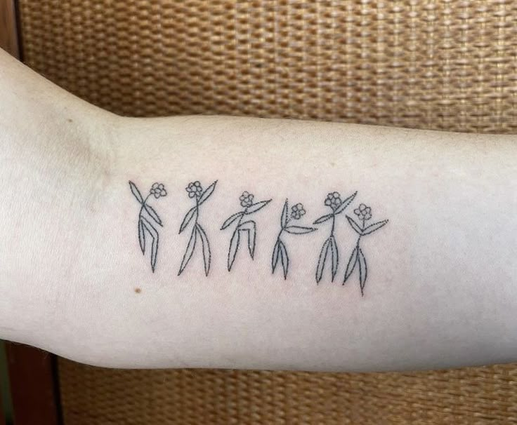 a person with a tattoo on their arm that has three people holding hands and flowers