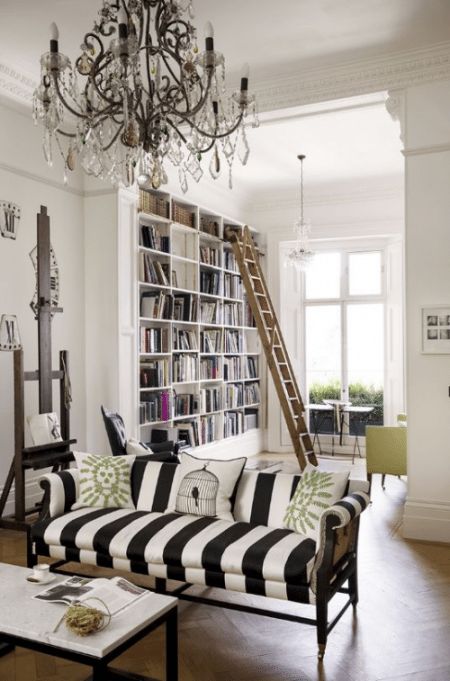 a living room filled with lots of furniture and a chandelier hanging from the ceiling