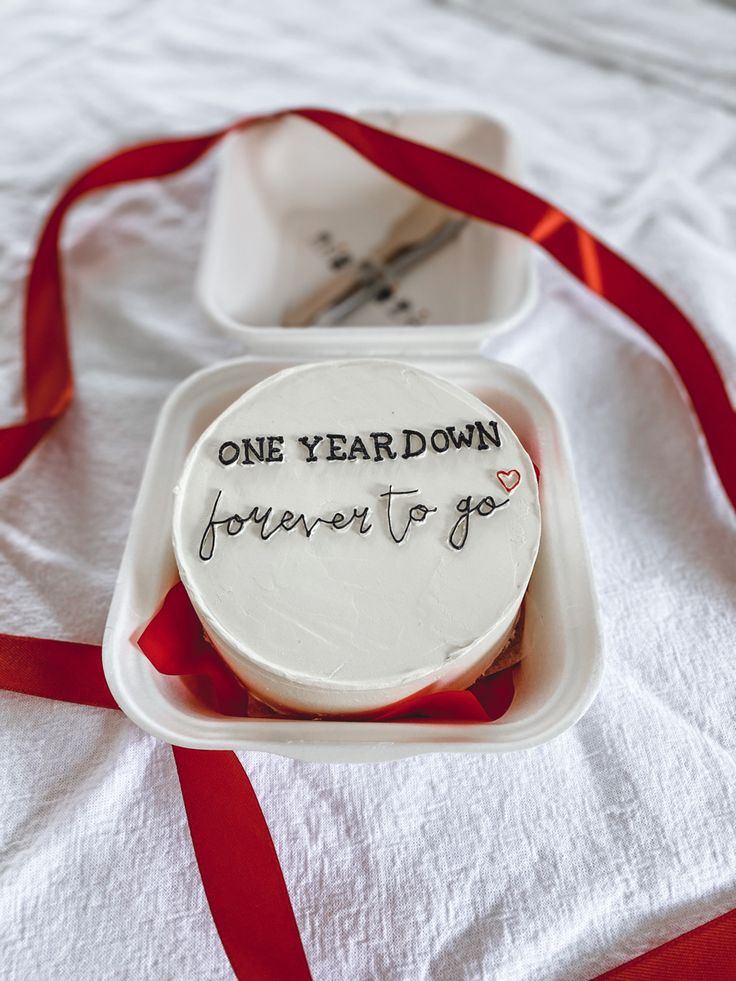 a birthday cake with the words one year down written on it and a red ribbon