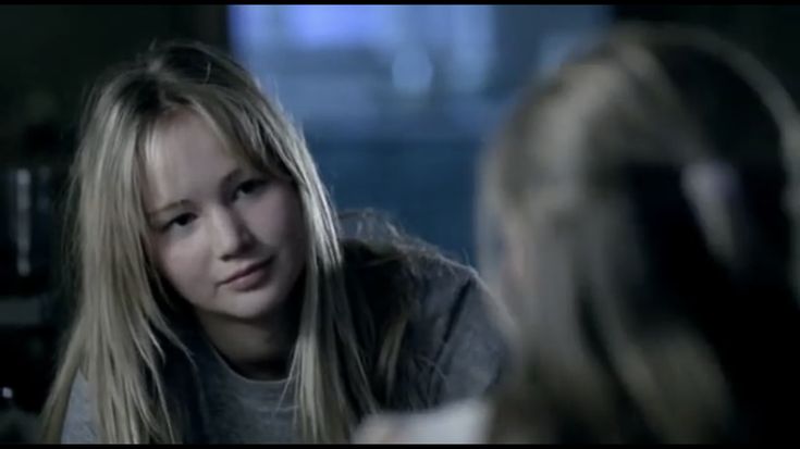 a young woman sitting in front of a mirror talking to another person with long blonde hair