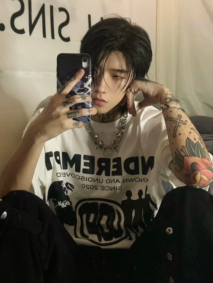 a young man with black hair and piercings is taking a selfie