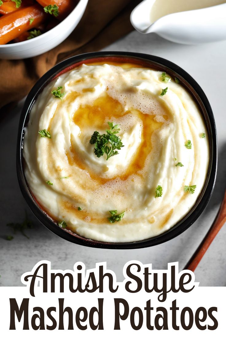 a bowl filled with mashed potatoes next to carrots and parsley on the side