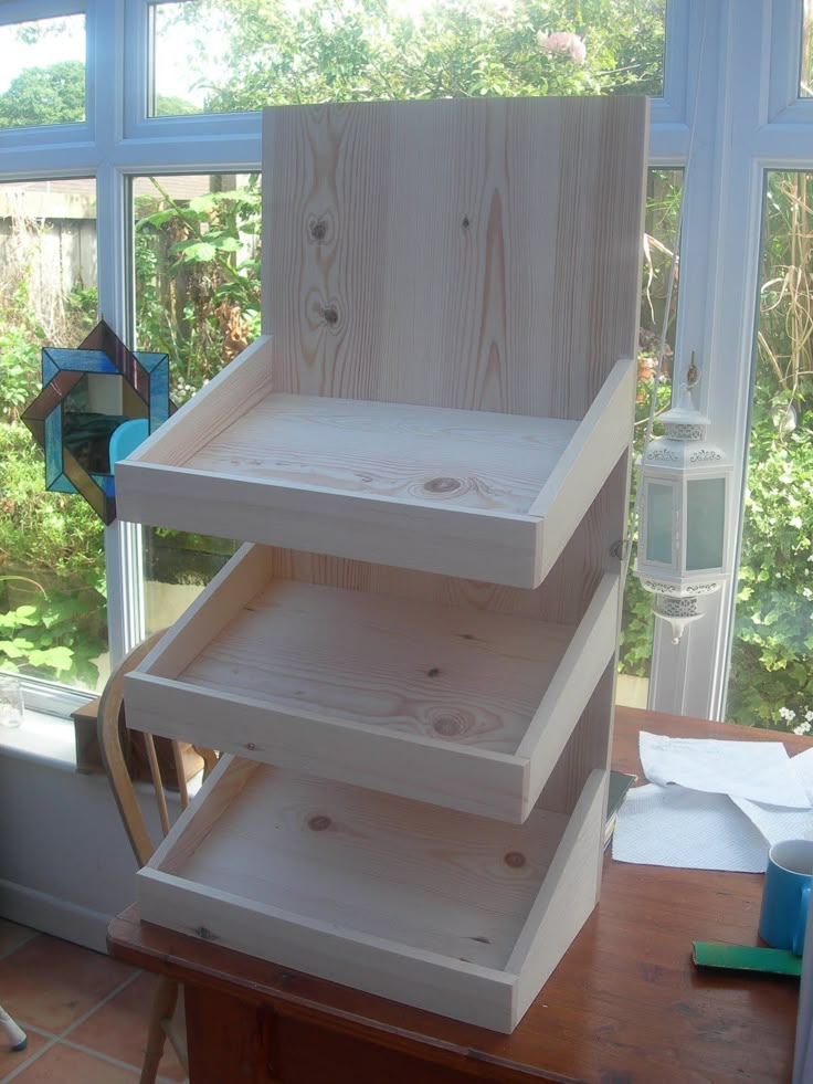 three shelves are stacked on top of each other in front of a window, near a desk