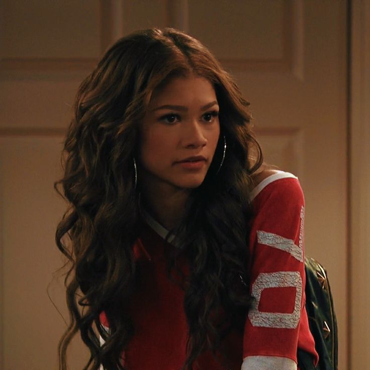 a woman with long hair wearing a red and white shirt is looking at the camera