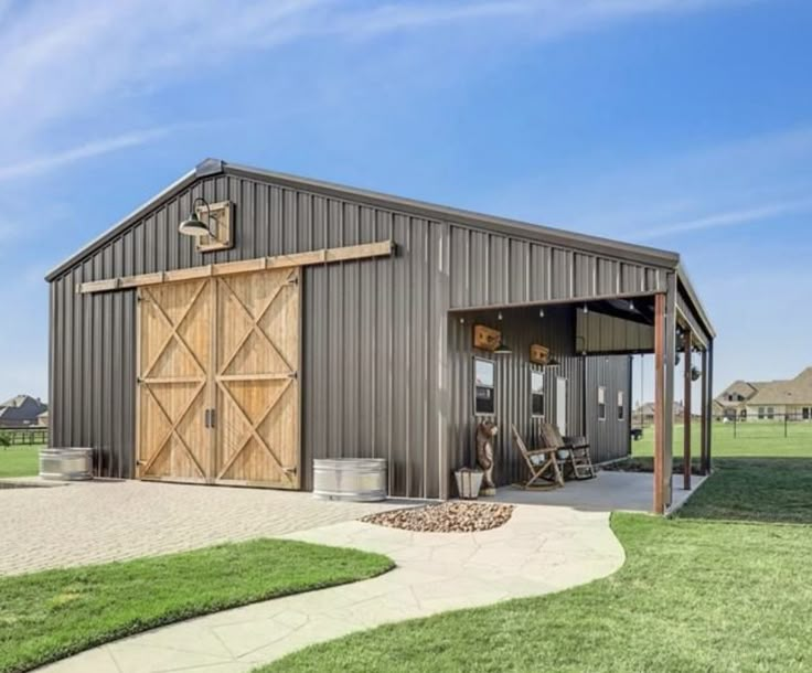 a large metal building with a wooden door on the side and grass in front of it