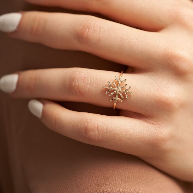 a woman's hand wearing a gold ring with a star design on the middle