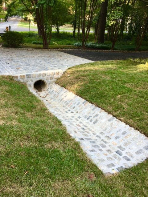 a brick walkway in the middle of a grassy area