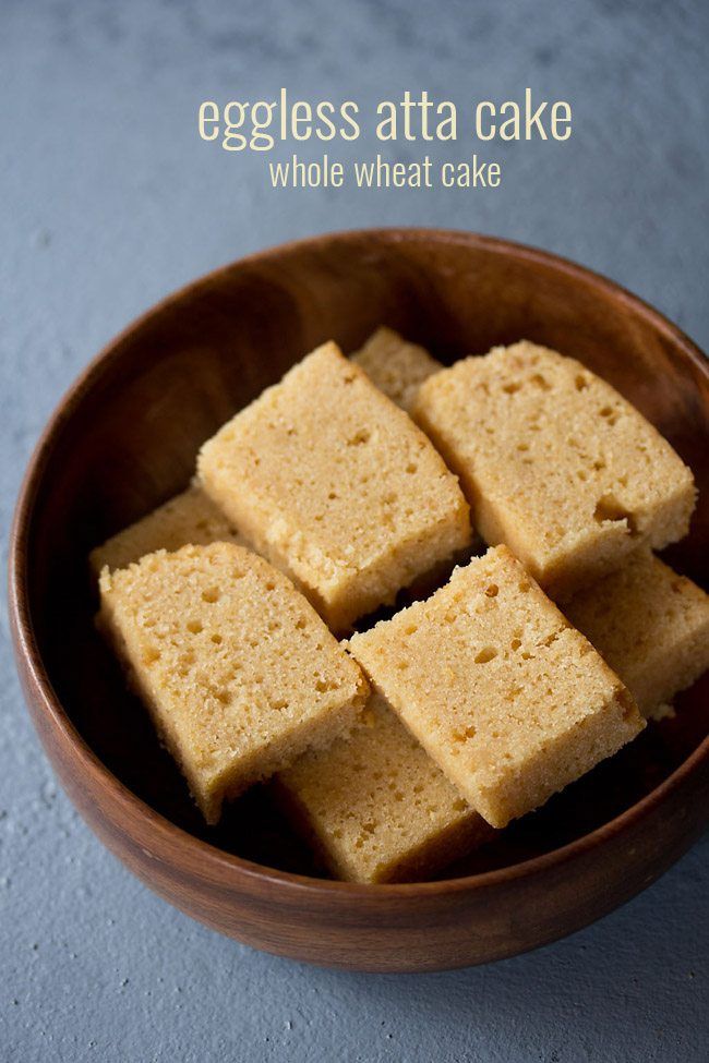 several pieces of cake in a bowl on a blue tablecloth with the words eggless whole wheat cake