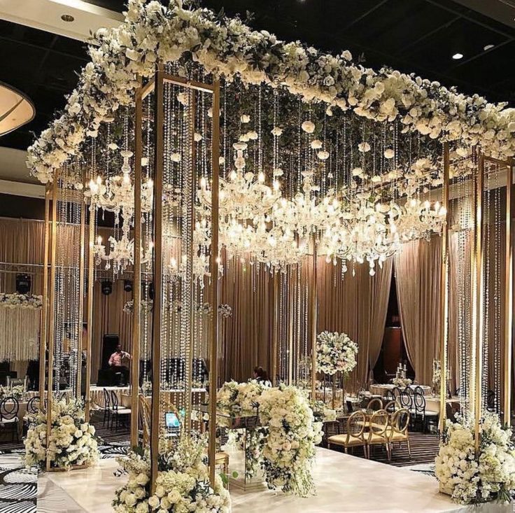 an elegant wedding setup with white flowers and chandelier hanging from the ceiling,