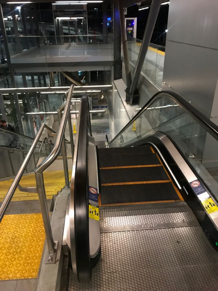 an escalator with stairs leading up to the second floor