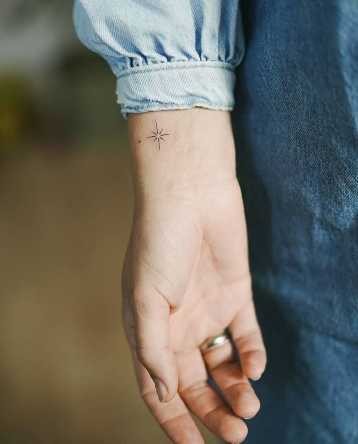 a person with a small star tattoo on their left hand, holding the other hand