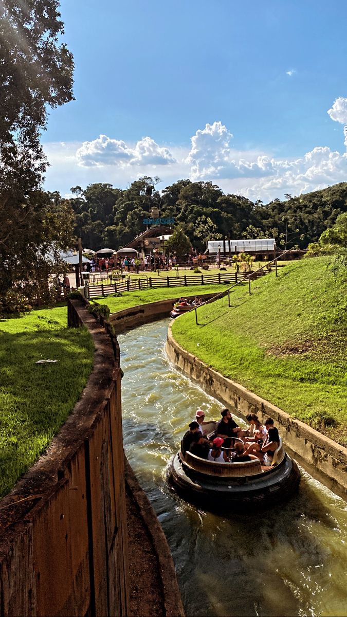 people are riding in a small boat on the water near a fence and grassy area