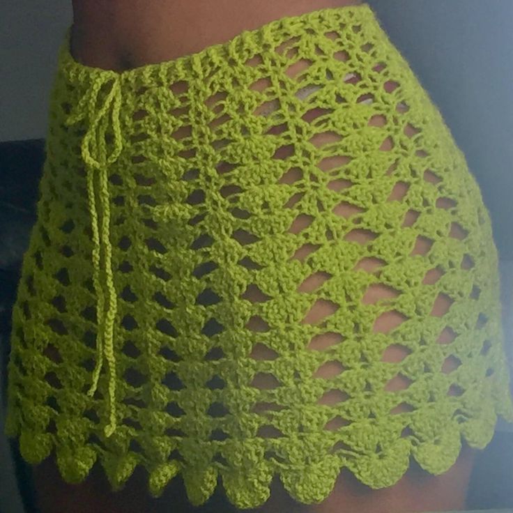 a woman wearing a yellow crochet skirt with an attached tie around her waist