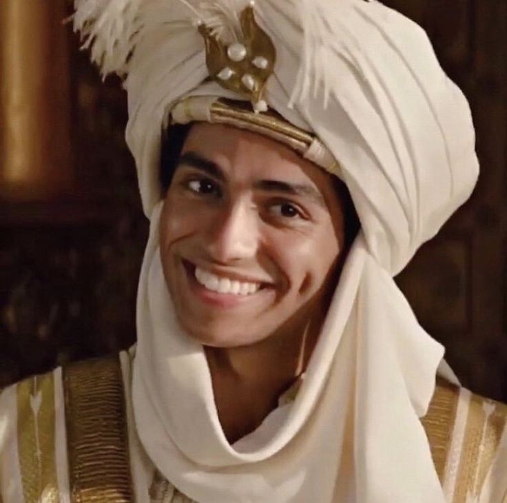 a man wearing a white turban smiles at the camera