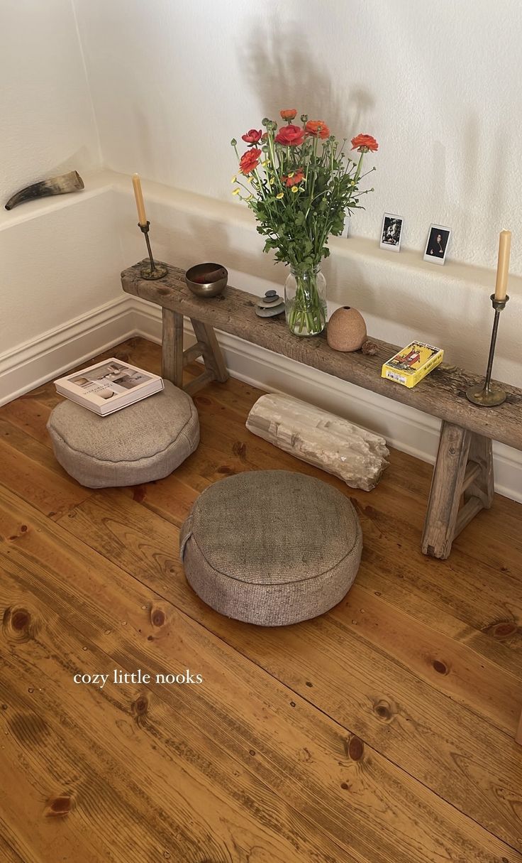 a room with two stools and a flower vase on the table next to it