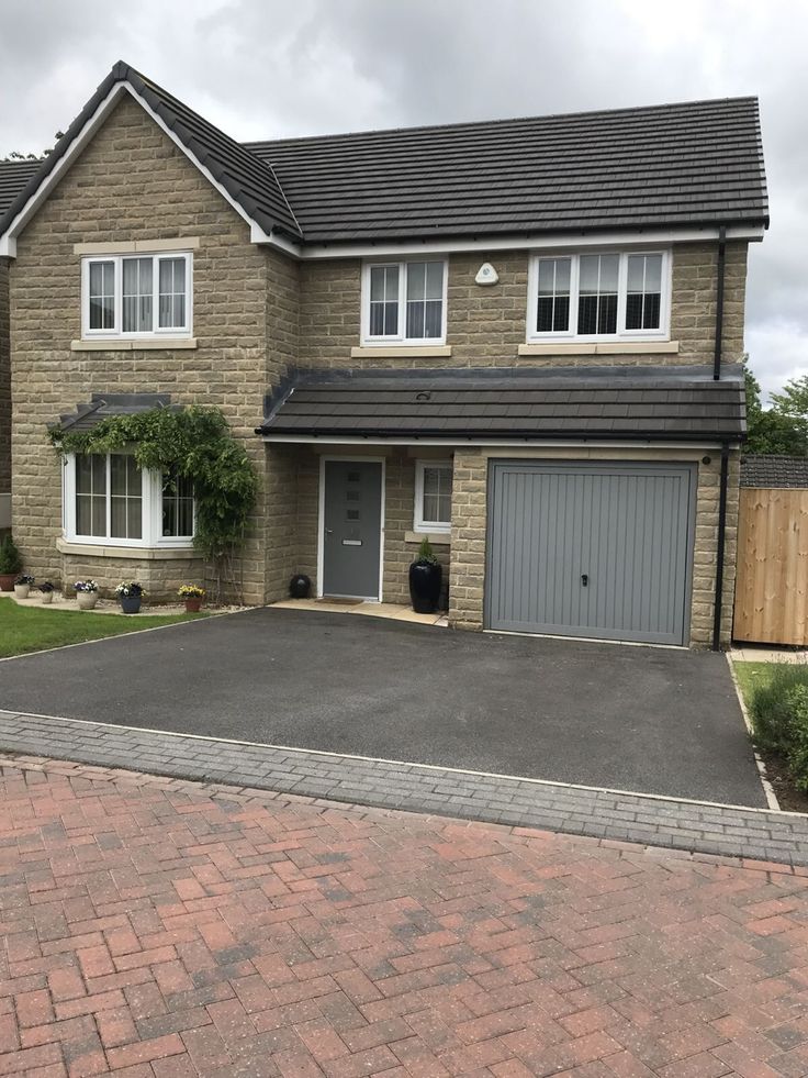 a two story brick house with grey garage doors and windows on either side of the driveway