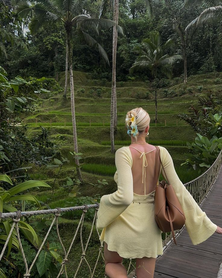 a woman walking across a bridge in the jungle